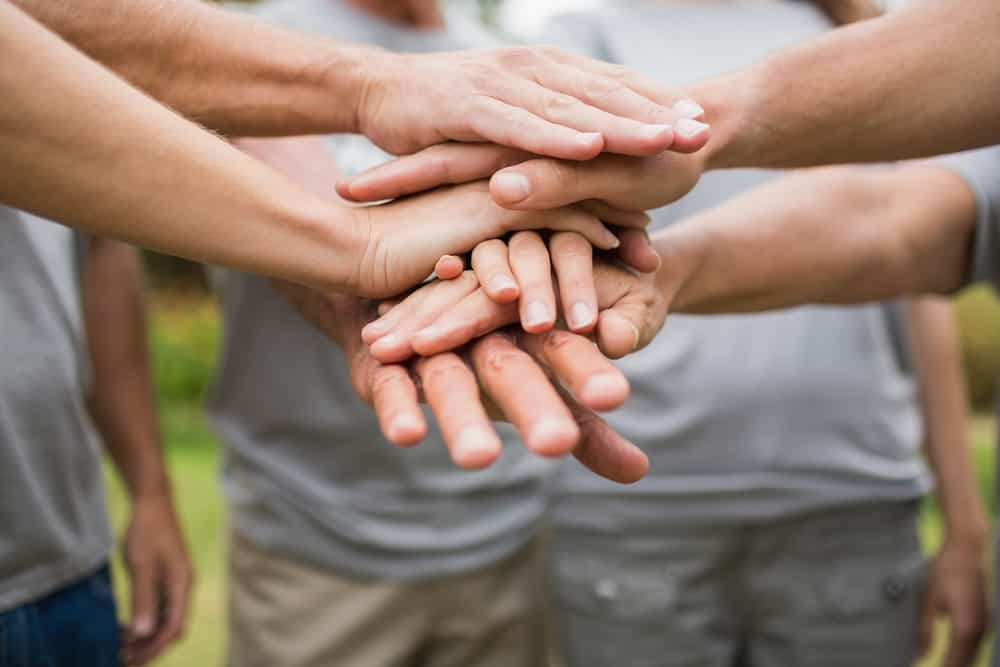 2020 Happy volunteer family putting their hands together on a sunny day